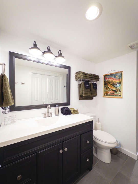 Bathroom vanity with a wide mirror and dark cabinets