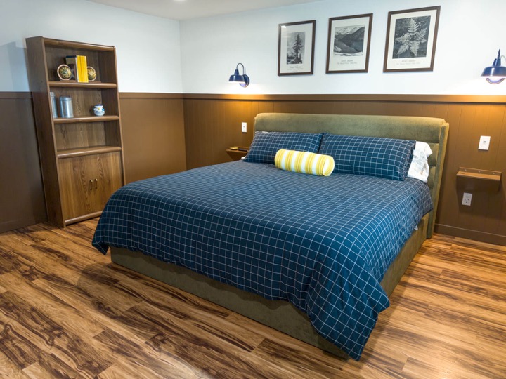 King bedroom with blue checked bedding, wood paneling, and park prints