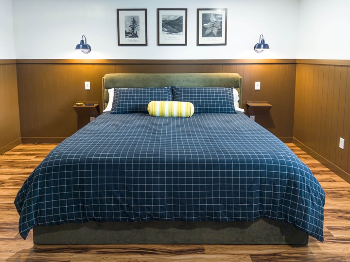 King bed with blue checked bedding and vintage park artwork