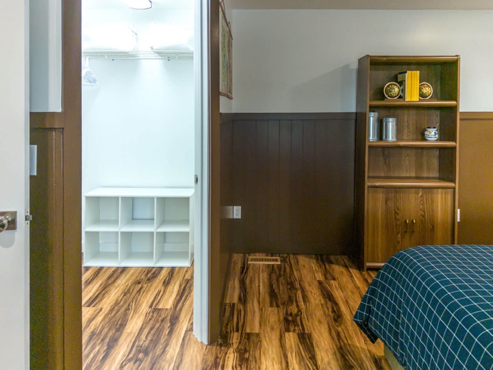 Wood-paneled king bedroom with a wardrobe and shelving