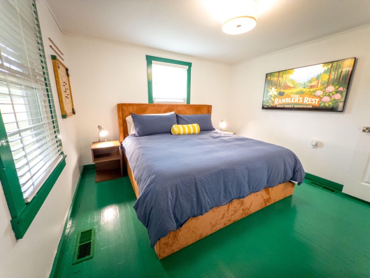 Second bedroom with blue bedding, green floors, and green trim