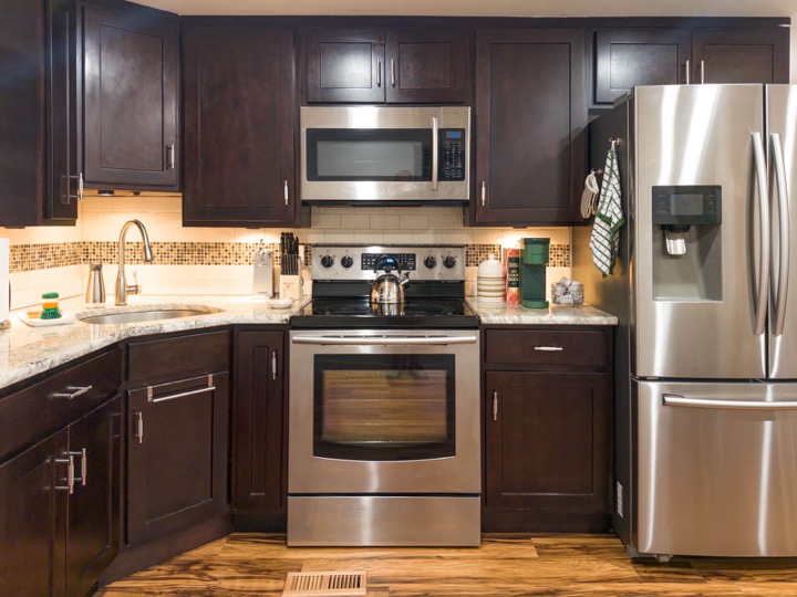 Kitchen with dark cabinets, stainless appliances, and a tile backsplash