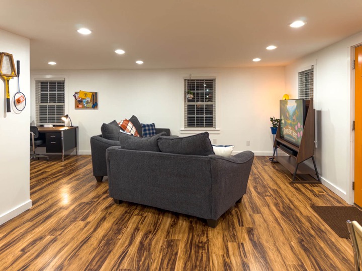 Open living room with gray sofas, wood floors, and warm lighting